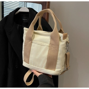Detail view of cream canvas tote bag with khaki handles and detachable shoulder strap