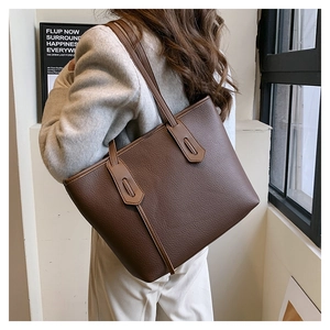 Side view of dark brown lychee grain leather tote bag with retro shield strap detail