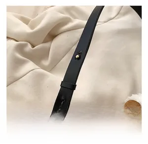 Détail de la bandoulière réglable en cuir noir avec rivets dorés et bordure de finition