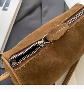 Close-up of smooth metal zipper and premium brown suede texture on a Boston cylinder bag