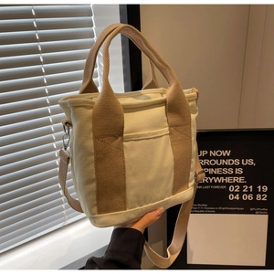 Detail of cream canvas tote bag showing the sturdy khaki strap and front pocket texture