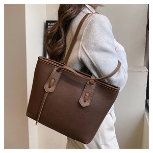 Macro detail of dark brown tote bag showing premium lychee grain leather and stitching