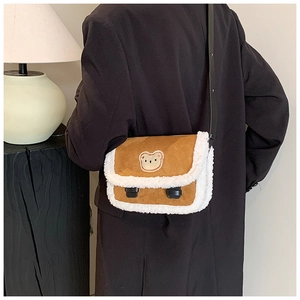 Sac bandoulière marron en peluche avec broderie d'ours porté par un mannequin en intérieur