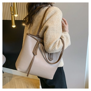 Detailed side view of high-capacity tote bag in beige with dark brown contrast handles
