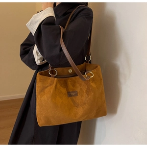 Detail of caramel suede tote bag with quilted pattern and dark brown leather shoulder straps