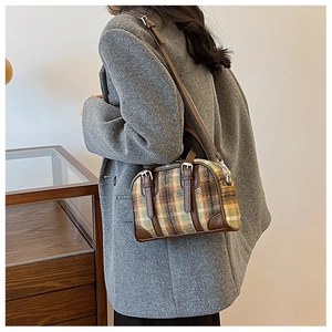 Detail view of a vintage plaid Boston bag with leather trim worn cross-body style