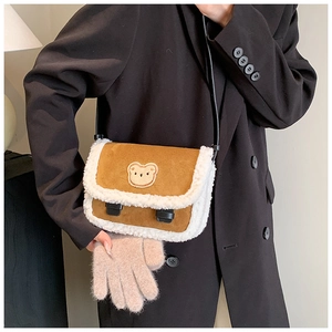 Détail d'un sac bandoulière en daim marron avec fourrure blanche et broderie ours