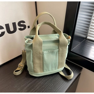 Close-up of light green canvas tote bag featuring reinforced stitching and front pocket
