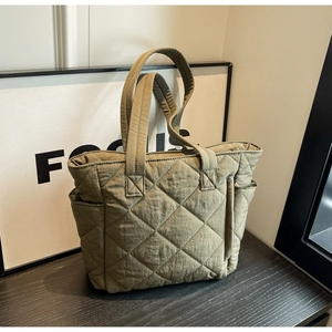 Detail view of the quilted nylon tote bag in olive green with functional side pockets