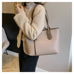 Detail of a large beige tote bag with litchi texture and contrasting brown shoulder straps