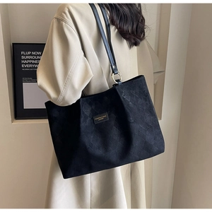 Detail of black quilted tote bag showing rhombus pattern and metallic buckle on shoulder strap