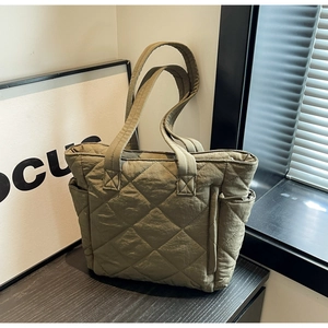 Detail of olive green quilted nylon tote bag with rhombus pattern and side pockets