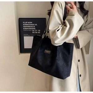 Detailed view of black quilted tote bag with matte texture on a female shoulder