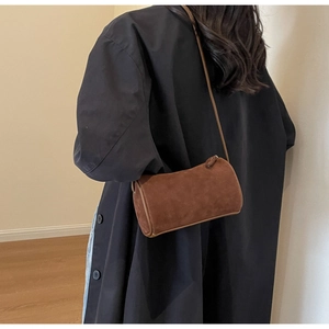 Rear view of model wearing a brown suede cylinder Boston crossbody bag for daily styling
