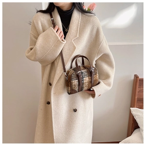 Brown and beige plaid wool Boston bag with leather handles shown on a beige coat