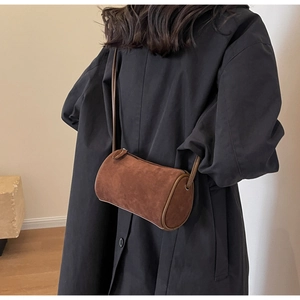 Macro detail of brown frosted suede cylindrical crossbody bag with minimalist leather strap