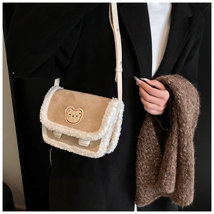 Détail du sac bandoulière en daim kaki avec bordure en laine blanche et broderie d'ours