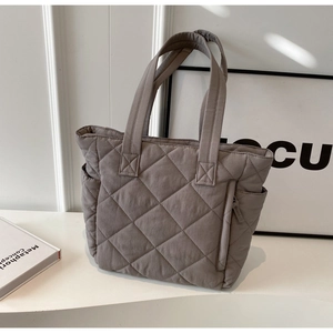 Detail of taupe quilted nylon tote bag showing diamond stitching and side pocket