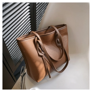 Close-up of the pebbled leather texture and dual shoulder straps on the brown tote bag