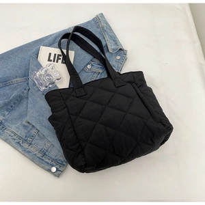 Close-up of black quilted nylon tote bag featuring diamond pattern on a white surface