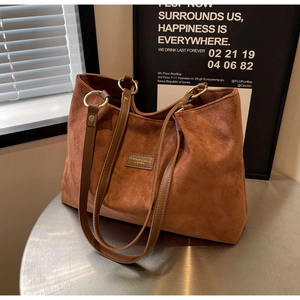 Detail of a brown frosted leather tote bag with gold metal rings and fashion label