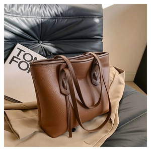 Close-up of brown litchi pattern leather tote bag with shield-shaped reinforced stitching