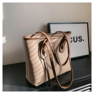 Detail of beige pebbled leather tote bag with brown straps and structured stitching