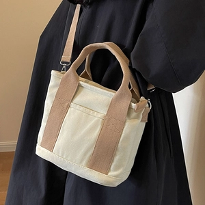 Minimalist canvas tote bag with brown straps shown in a crossbody and handheld style