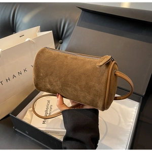 Detailed view of a brown suede Boston barrel bag with metal zipper and fine stitching