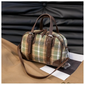 Detail of green plaid wool fabric and premium brown leather handle on Boston bag
