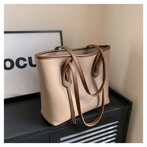 Detail of beige pebbled leather tote bag with contrasting brown trim and sturdy handle