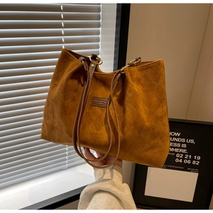Detail of caramel suede tote bag with diamond quilting and leather brand patch