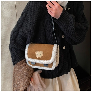 Détail d'un sac bandoulière en suède marron avec bordure en polaire et broderie