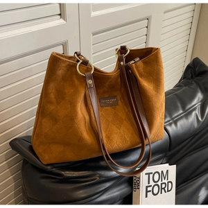 Detail of a brown quilted matte leather tote bag with a metal ring and fashion label