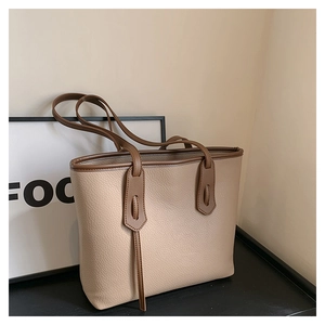 Detailed shot of beige lychee texture tote bag with brown contrast stitching and straps