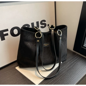 Detail of black frosted leather tote bag with quilted diamond stitching and gold metal rings