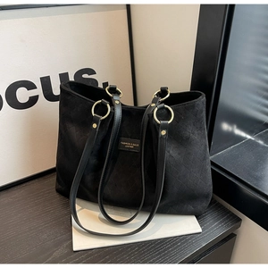 Close-up of black diamond-quilted matte tote with gold rings and leather handle