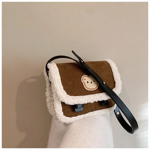 Détail du sac à bandoulière en daim marron avec bordure en peluche et ours brodé