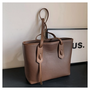 Close-up of deep brown tote bag showing premium lychee grain leather texture and handle detail