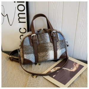 Detail of plush plaid Boston bag with leather straps and handles on a cozy background