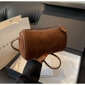 Detailed macro shot of caramel suede cylinder bag with silver zipper and white stitching