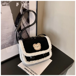 Détail du sac bandoulière noir avec bordure en fausse fourrure blanche et ours brodé
