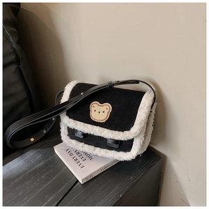 Détail du sac bandoulière d'hiver avec bordure en fourrure, écusson ours et tissu mat
