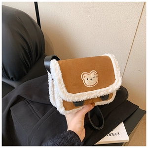 Détail d'un sac bandoulière en daim marron avec bordure en polaire et broderie ours