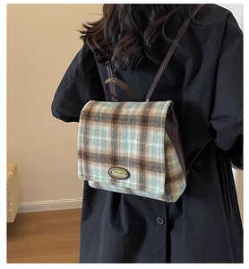 Detail of the vintage plaid backpack featuring tweed fabric and leather strap on a model