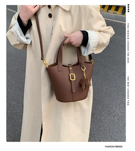 Detailed view of brown pebbled leather bucket bag with gold hardware and elephant charm