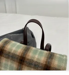 Close-up of checkered flap backpack featuring wool fabric and brown leather handle