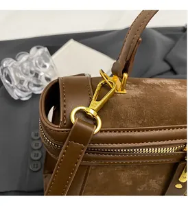 Detail einer braunen Ledertasche mit goldfarbenen Beschlägen und hochwertigen Nähten