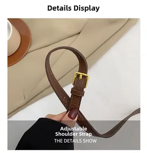 Detail of adjustable brown leather shoulder strap with gold metal buckle on bucket bag