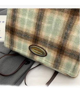 Detail of wool-like plaid handbag featuring classic check pattern and metal logo plate